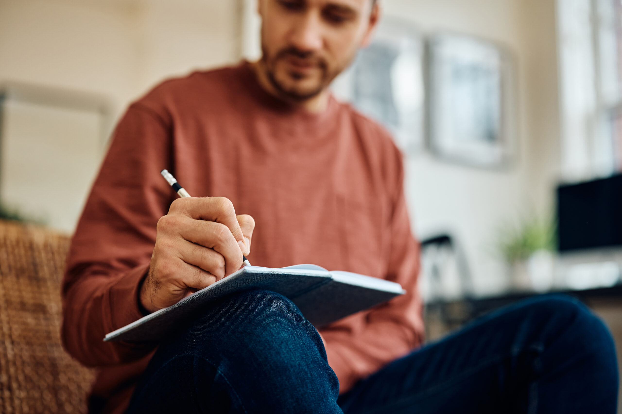 Close up of man writing in notebook at home.