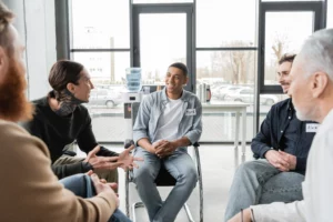 tattooed man with alcohol addiction talking to group