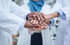 shot of a group of unrecognisable scientists joining hands
